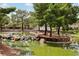 Scenic backyard pond featuring mature trees, natural rock formations, and a small island, creating a serene escape at 3201 Beacon Shores Cir, Las Vegas, NV 89117