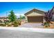 Two car garage with a stone veneer trim and desert landscaping at 3484 Bradano Ln, Henderson, NV 89044