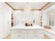 This walk-in closet features white cabinets, copper accents, a marble island, and a beautiful chandelier at 454 Rosina Vista St, Las Vegas, NV 89138