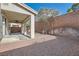 View of the backyard with a covered patio, low brick wall, gravel landscaping, and mature trees at 4744 Deer Forest Ave, Las Vegas, NV 89139