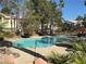 Community pool with seating and umbrellas providing shade, with palm trees and greenery surrounding at 5222 Mandalay Springs Dr # 202, Las Vegas, NV 89120