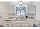 Bright kitchen features white cabinets, stainless steel sink, and window with blue curtains at 601 Huntington St, Las Vegas, NV 89107