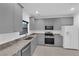 A modern kitchen featuring gray cabinets, granite countertops, and stainless steel appliances at 69 Ella Ashman Ave, Henderson, NV 89011