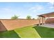 Spacious backyard featuring synthetic grass, a brick wall, and covered patio at 6901 Whisper Canyon Pl, North Las Vegas, NV 89084