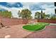 Well-maintained backyard featuring a picnic table, artificial turf, gravel, and a brick privacy wall at 7372 S Palo Real Ct, Las Vegas, NV 89179