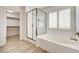 Bright bathroom featuring a tub, glass shower, and shuttered window at 7372 S Palo Real Ct, Las Vegas, NV 89179