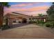 Majestic home with portico entry, circular driveway, and mature landscaping against a vibrant sunset sky at 9111 W Stephen Ave, Las Vegas, NV 89149