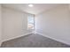 An empty carpeted bedroom with a bright window providing natural light, and light neutral walls at 9321 Dancing Daffodil Ave, Las Vegas, NV 89129