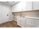 Updated laundry room with white cabinets, quartz countertops, and wood-look flooring at 1016 Eaglewood Dr, Las Vegas, NV 89144