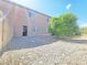 View of the backyard showing gravel ground cover, partial fence, mature tree and back of home at 1951 Teepee Rd, Pahrump, NV 89048