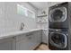 Well-appointed laundry room featuring gray cabinets, marble countertops, and a stacked washer and dryer at 2250 Bowie Cir, Henderson, NV 89014