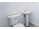 Modern half-bathroom with sleek fixtures, pedestal sink, toilet, and wood-look flooring at 2501 Indigo Mountain St, Henderson, NV 89044