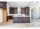 Modern kitchen featuring dark wood cabinetry, stainless steel appliances, and a center island with white countertop at 2501 Indigo Mountain St, Henderson, NV 89044