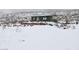 Winter view of small, green house with snow-covered landscape and boulder accents at 275 Vegas Dr, Goodsprings, NV 89019