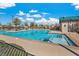 Community pool featuring a large pool with lounge chairs and umbrellas under a bright blue sky with fluffy white clouds at 3188 Via Da Vinci, Henderson, NV 89044