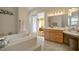 Bathroom featuring a tile-enclosed tub, vanity with lighting, and an open doorway at 404 Via Sonador, Henderson, NV 89012