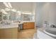 Bathroom with a tub, mirrors, dual sinks, and tiled floors, offering a relaxing space at 404 Via Sonador, Henderson, NV 89012