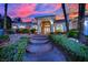 Charming single-story home with manicured landscaping, brick accents, and a welcoming entrance with brick steps at sunset at 4418 Desert Bloom Ct, Las Vegas, NV 89129