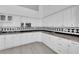 Modern kitchen with white cabinetry, black and white backsplash, and wood-look flooring at 4418 Desert Bloom Ct, Las Vegas, NV 89129