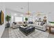 Bright, staged living room with elegant decor, two sofas, marble table, chandelier and fireplace at 4418 Desert Bloom Ct, Las Vegas, NV 89129