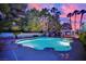 A beautiful pool with a hot tub and lush tropical landscaping under a colorful sunset at 4418 Desert Bloom Ct, Las Vegas, NV 89129