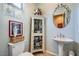 Cozy powder room with a pedestal sink, wall mirror, and decorative details at 4719 Riva De Romanza St, Las Vegas, NV 89135