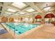 Bright indoor pool with clear blue water, arched windows, and comfortable lounge chairs for relaxation at 4719 Riva De Romanza St, Las Vegas, NV 89135