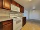 Practical kitchen features wood cabinets, white appliances, and view to living area at 4943 Indian River Dr # 133, Las Vegas, NV 89103