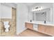 Renovated bathroom showcasing double sinks, wood vanities, modern fixtures, and a tiled shower at 6717 Sheffield Dr, Las Vegas, NV 89108