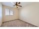 This bedroom has neutral walls and carpet, a ceiling fan, and large sunny window at 7382 Elbridge Way, Las Vegas, NV 89113