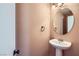Neat half bathroom with a pedestal sink and a round mirror, perfect for guests at 7382 Elbridge Way, Las Vegas, NV 89113
