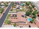 This aerial showcases a tile-roofed home with solar panels and a pool, nestled amongst manicured lawns and mature trees at 7408 Via Fiorentino St, Las Vegas, NV 89131