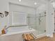 Bright main bathroom with a soaking tub, shower, and neutral tile flooring at 7408 Via Fiorentino St, Las Vegas, NV 89131