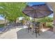 Outdoor kitchen with a built-in grill and seating under an umbrella, surrounded by lush greenery and landscaping at 7408 Via Fiorentino St, Las Vegas, NV 89131