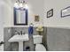Charming powder room with pedestal sink, decorative mirror and tasteful wall art at 7408 Via Fiorentino St, Las Vegas, NV 89131
