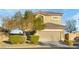 Two-story home with a beige exterior, a two car garage and professional landscaping at 8036 Eurostar St, Las Vegas, NV 89131