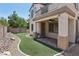 Landscaped backyard with artificial grass, brick-paved patio, and lush greenery, creating a private outdoor retreat at 8204 Chimney Bluffs St, North Las Vegas, NV 89085
