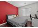 Cozy bedroom featuring stylish black and white bedding, hardwood floors and red accent wall, desk, and natural light at 9053 Boston Springs Ave, Las Vegas, NV 89149