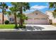 Charming single-story home featuring a two-car garage, lush lawn and mature palm trees at 9205 Desert Village Ave, Las Vegas, NV 89147