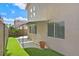 Backyard view with artificial grass, a covered patio, and a beige stucco exterior at 927 Clear Diamond Ave, Las Vegas, NV 89123