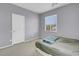 Bedroom featuring a neutral carpet, a single window, and a simple white door, providing a blank canvas at 9840 Chief Sky St, Las Vegas, NV 89178