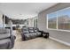 Open-concept living room with leather sofa and chair, large windows, and view into the kitchen at 9840 Chief Sky St, Las Vegas, NV 89178