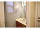 Cozy half bathroom with a wood vanity, silver hardware, a framed mirror, and a window for natural light at 10449 Yew Blossom Ave, Las Vegas, NV 89166