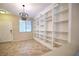 The living room showcases tile floors, a modern chandelier, a bright window and built-in bookshelves at 10449 Yew Blossom Ave, Las Vegas, NV 89166