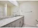 Bright bathroom with a granite countertop, neutral cabinets, and large mirror at 10974 Cheshire Woods Ave, Las Vegas, NV 89166