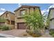 Charming home featuring a two-car garage, complemented by desert landscaping and a brick driveway at 10974 Cheshire Woods Ave, Las Vegas, NV 89166