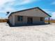 Rear exterior of home features a covered patio and neutral stucco, plus rock landscaping at 1500 E Laguna St, Pahrump, NV 89048