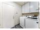 Well-lit laundry area with white washer and dryer, overhead cabinets, and convenient door access at 1740 Leaning Pine Way, Las Vegas, NV 89128
