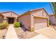 Tan home featuring a two-car garage, desert landscaping, and a walkway leading to the front door at 2106 King Mesa Dr, Henderson, NV 89012