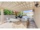 Outdoor kitchen and seating area under pergola with tropical landscaping at 2168 Big Bar Dr, Henderson, NV 89052